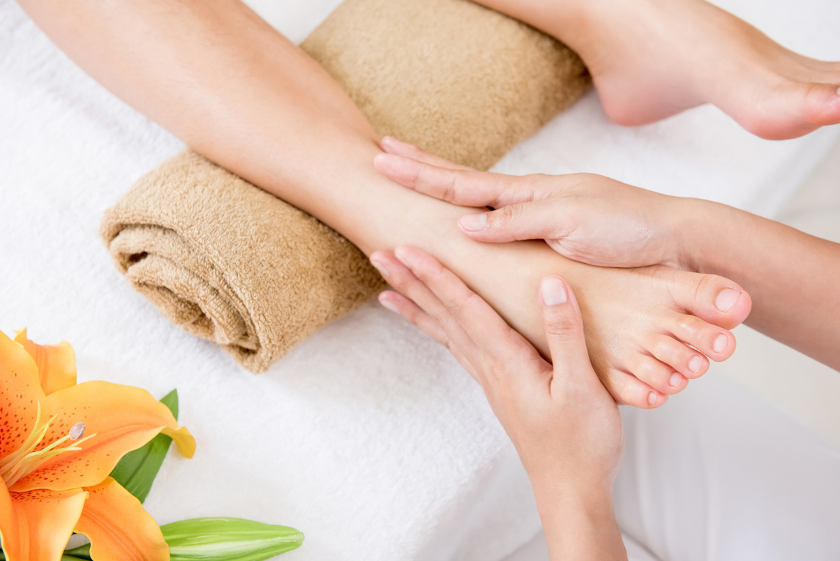 Therapist giving relaxing traditional reflexology foot massage to a woman in spa